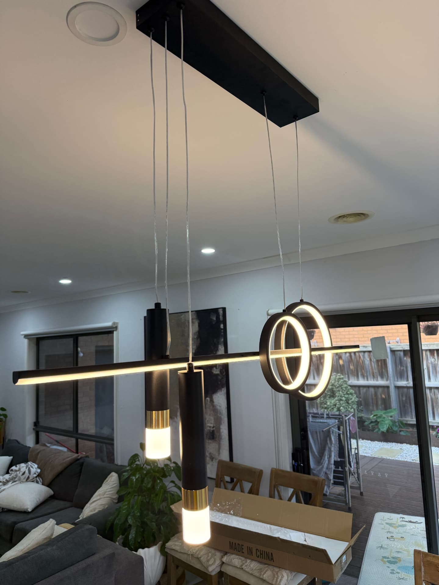 Modern black pendant light bar installed above a dining table